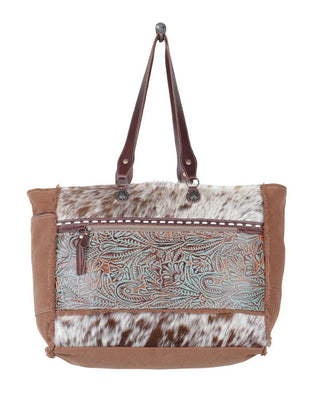 Handbag with brown leather handle and cowhide accents on a white background