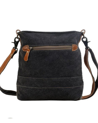 Black canvas crossbody bag with brown leather accents on a white background