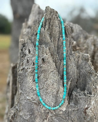 Turquoise beaded necklace on a textured wooden surface