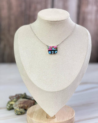 Necklace with a colorful pendant on a mannequin bust against a neutral background