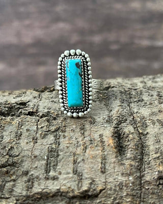 Silver ring with turquoise stone on a wooden surface