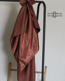 The Wynonna Wild Rag in Dark Coffee tied onto a metal railing with a wooden chair in the background.