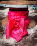 The Wynonna Wild Rag in Hot Pink tied to a wooden cable reel, resting on cowhide.