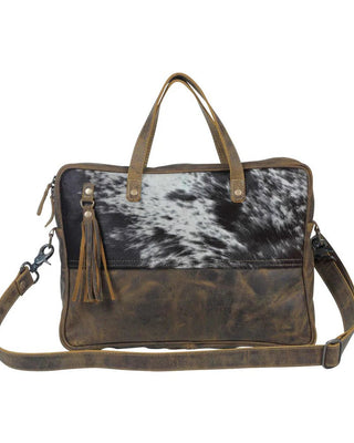 A rectangular leather shoulder and top-handle bag with a cowhide-patterned front panel and distressed brown leather lower section and straps, shown on a plain white background.