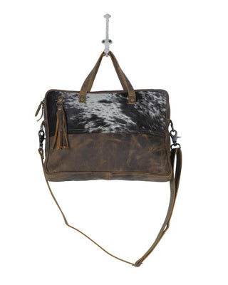 Brown leather bag with cowhide pattern on a white background