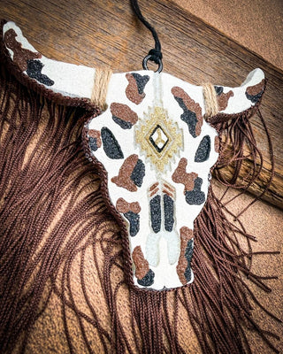 Black, brown, white, cow print bull skull car freshie, laying on wood
