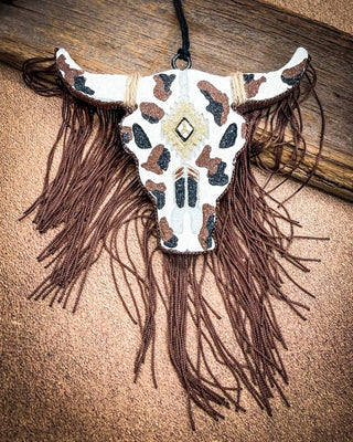Black, brown, white, cow print bull skull car freshie, laying on wood