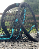 Hay net with teal and black design on a gravel surface