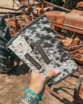 Hand holding a cowhide wallet with rustic background