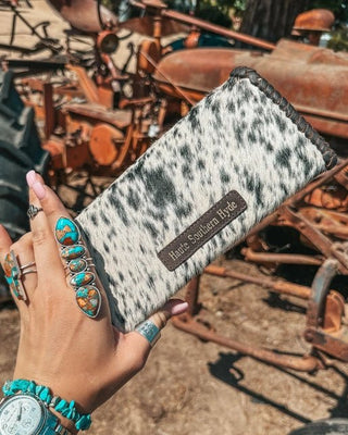 Hand holding a cowhide wallet with rustic background