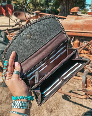Hand holding an open black leather wallet with a rustic background