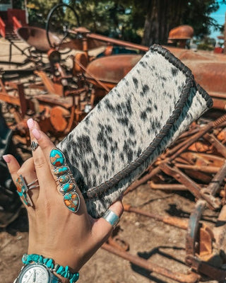 Hand holding a cowhide wallet with a rustic background