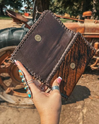 Hand holding a brown leather wallet with rustic background