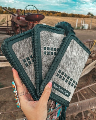 Hand holding three patterned wallets with a rustic background