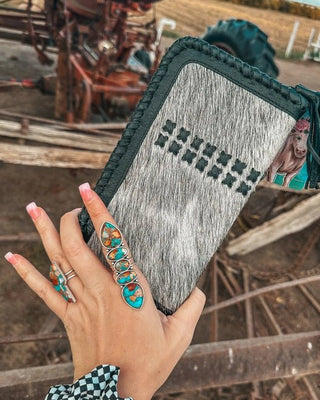 Hand holding a patterned clutch with a rustic background