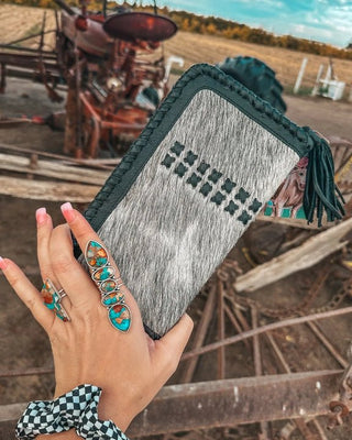 Hand holding a wallet with a rustic background of machinery and open field.