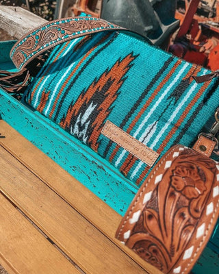 Turquoise saddle blanket purse with brown and white pattern on a wooden surface