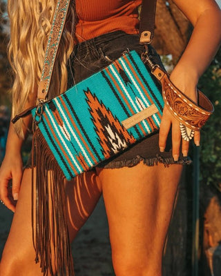 Person holding a colorful patterned handbag with fringes outdoors