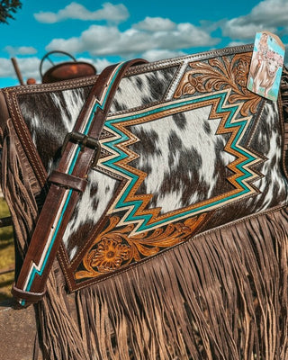 Close-up of a decorative bag with intricate patterns and fringes, set against a natural outdoor background.
