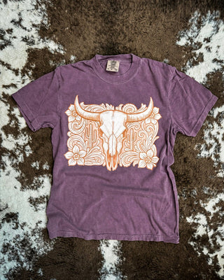 Wine shirt with a tooled western bull skull design on a cowhide rug.