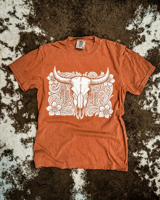 Rust shirt with a tooled western bull skull design on a cowhide rug.