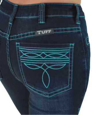 Close-up of the back pocket of dark blue denim jeans with turquoise contrast stitching and a decorative embroidered pattern. A small black brand patch reading TUFF is visible above the pocket.