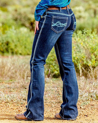 Woman wearing a blue shirt and jeans with a cowboy hat in a desert landscape