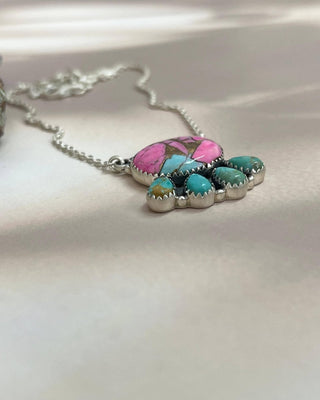 Necklace with a pink and turquoise stone on a light background